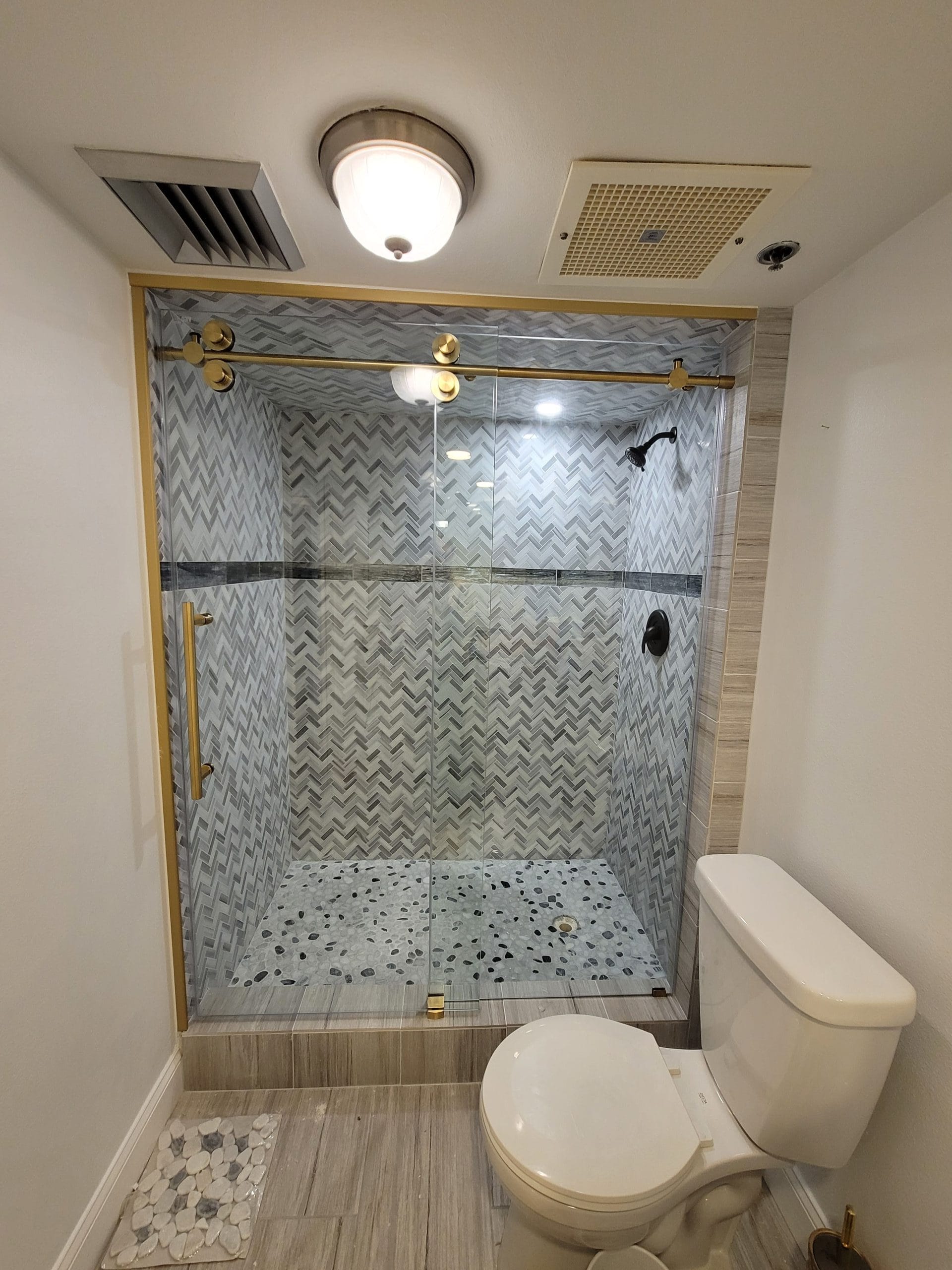 Herringbone-Shower-Tile-With-Gold-Hardware