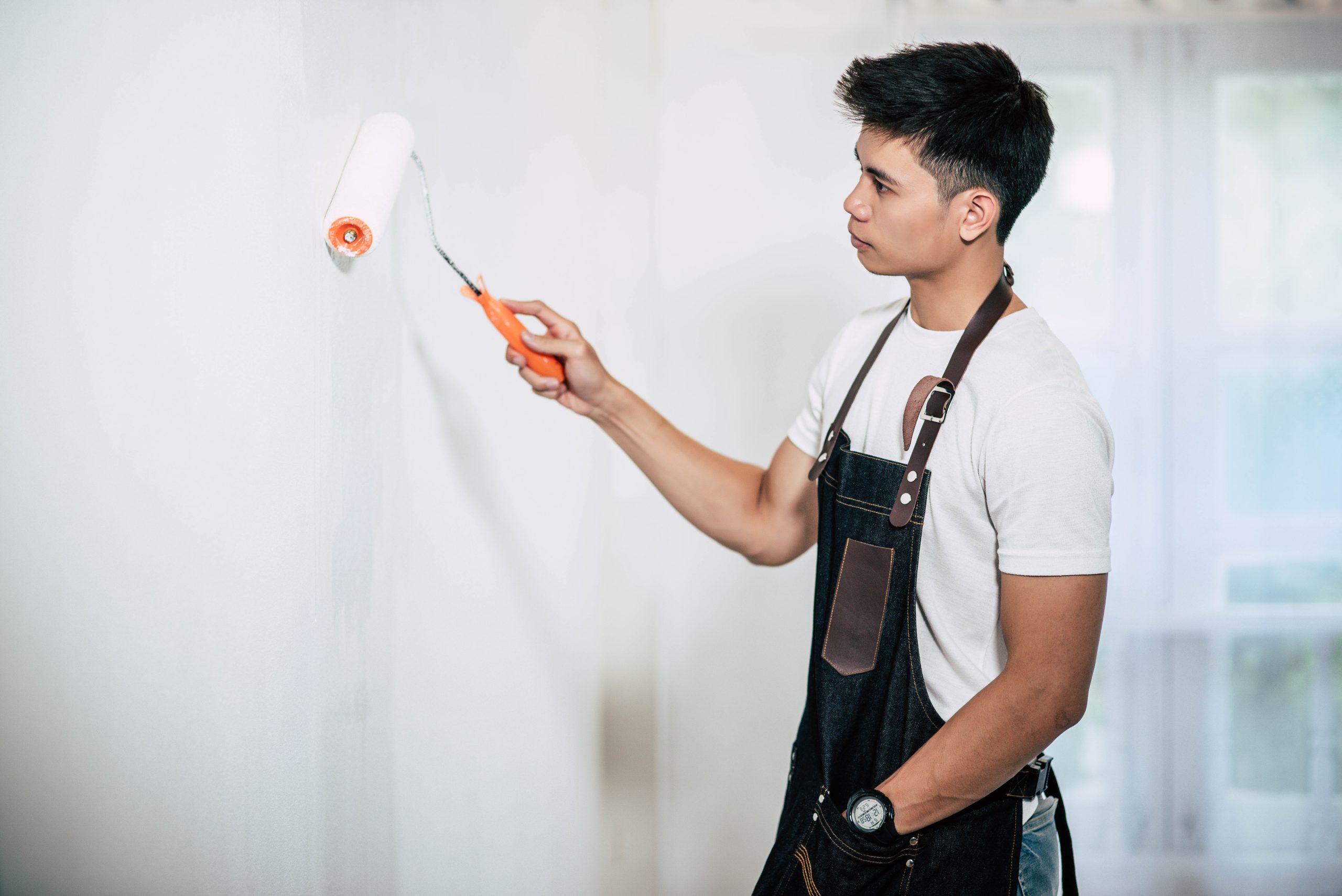 A carpenter holds a paintbrush and paints wood. Selective focus.